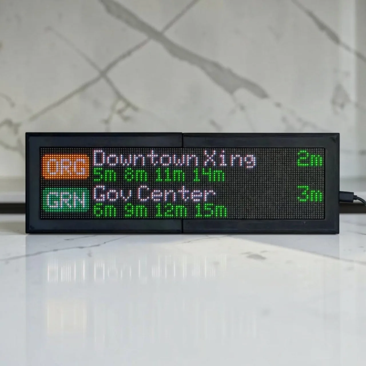 CommuteLive display on a marble counter showing Boston MBTA arrivals