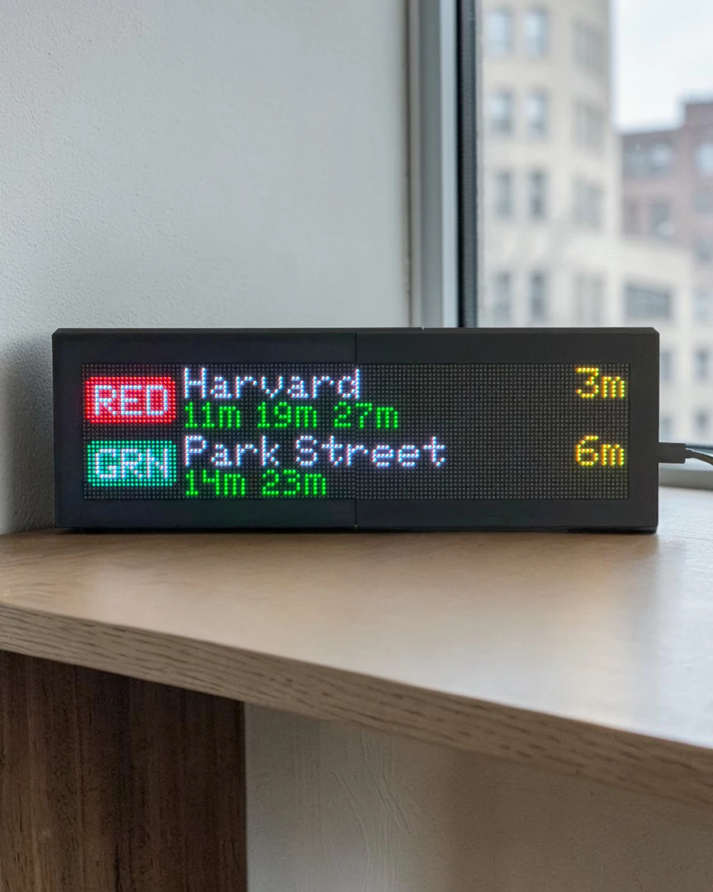Close-up of a CommuteLive LED board showing Penn Station in 3 minutes lit amber for a delay